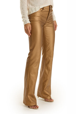 A person showcases the Aria Coated Flare Jean - Gold Metallic with a cream long-sleeve sweater, standing with feet apart to highlight the outfit’s full length—an elegant look echoing the luxe, metallic finish of these jeans.