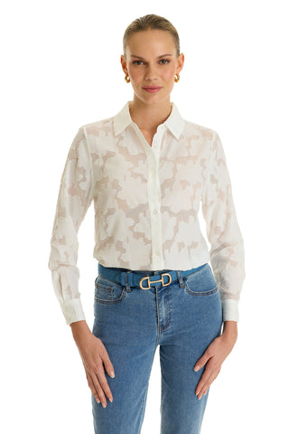 A woman models the Stelle Button Up - White, a sheer floral lace blouse styled with high-waisted blue jeans and a double-ring belt. She wears gold hoop earrings, has slicked-back hair, and poses against a white background.