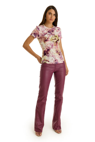 A woman with long brown hair stands against a white background, wearing the Amaya Ultra-Soft T-Shirt in French Garden and high-waisted, flared magenta pants with open-toed heels. She has a neutral expression.