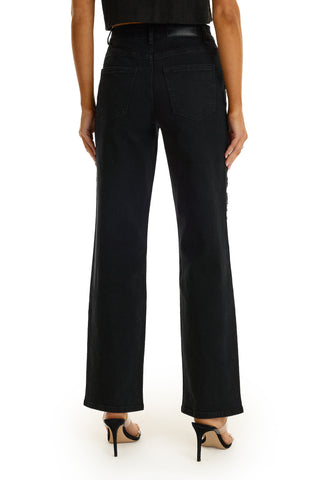 A woman is shown from the back against a white background wearing the Stassi Floral Sequin Jean in black paired with black heeled sandals.