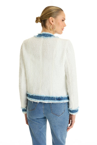 A woman with blonde hair in a low bun wears the Julia Tweed Jacket - Denim/White, featuring textured white tweed with blue denim trim and light blue jeans. She stands with her back to the camera against a white background.