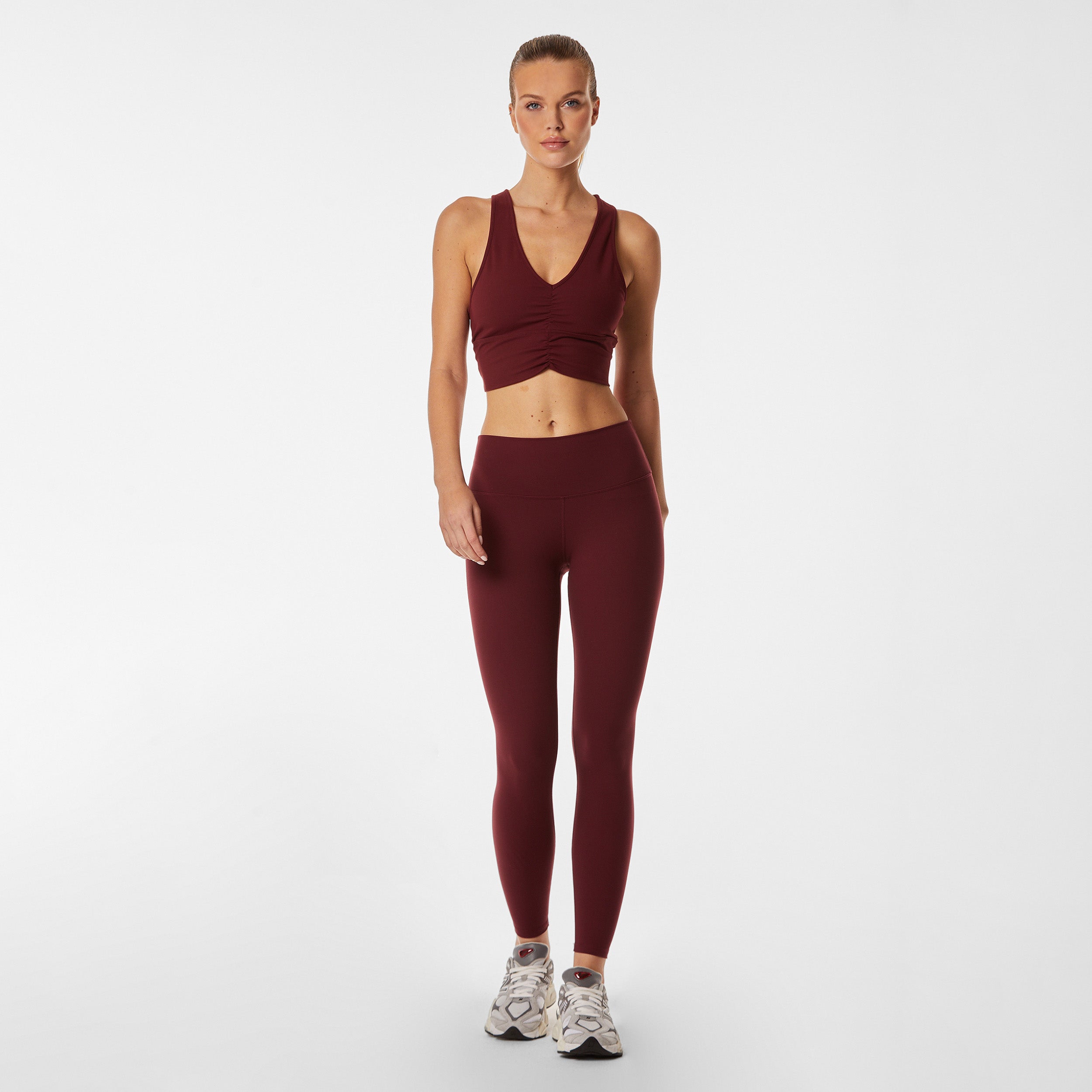 Full body view of woman wearing ruched front red racerback bra and matching legging