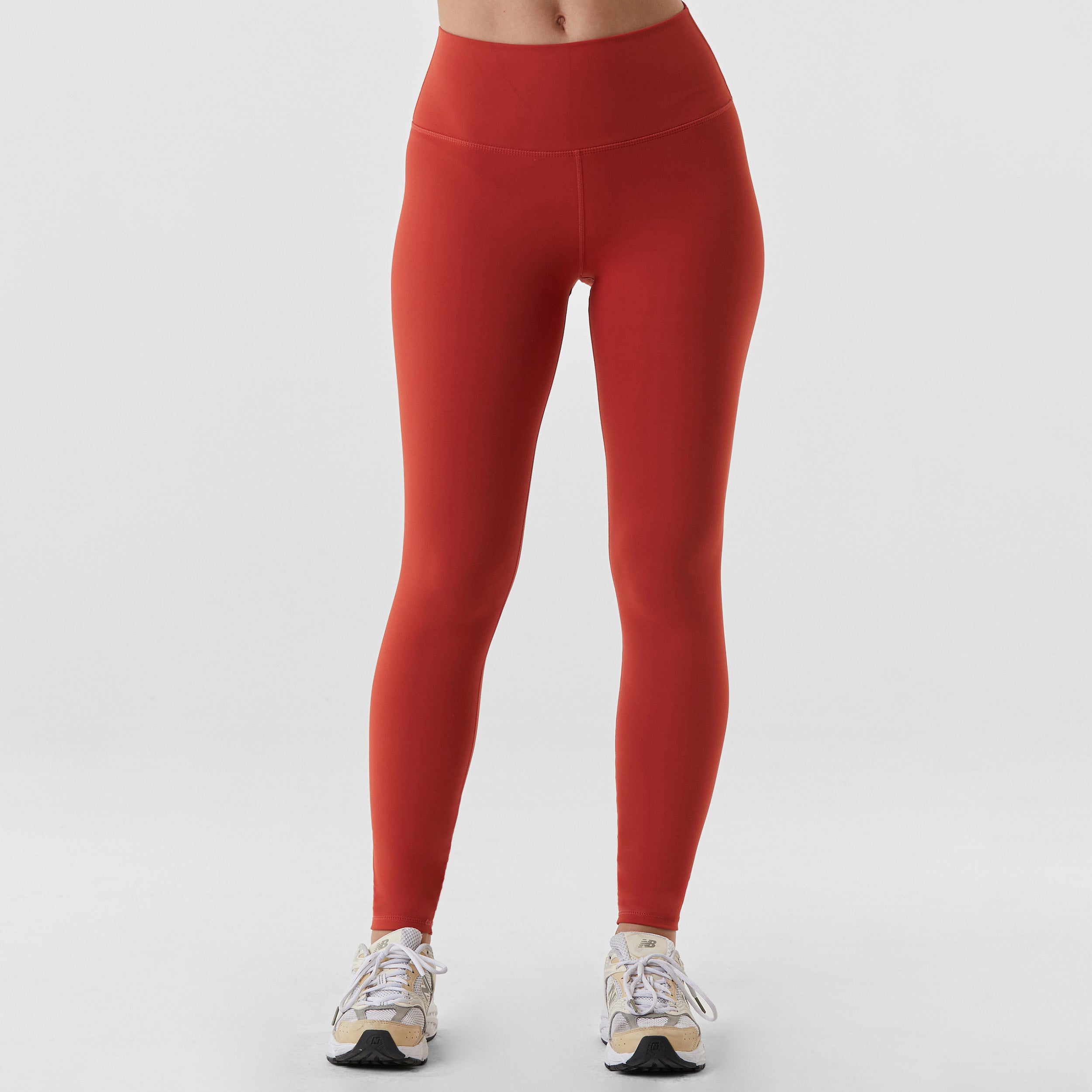 Front view of woman wearing sculpting and flattering brick red legging