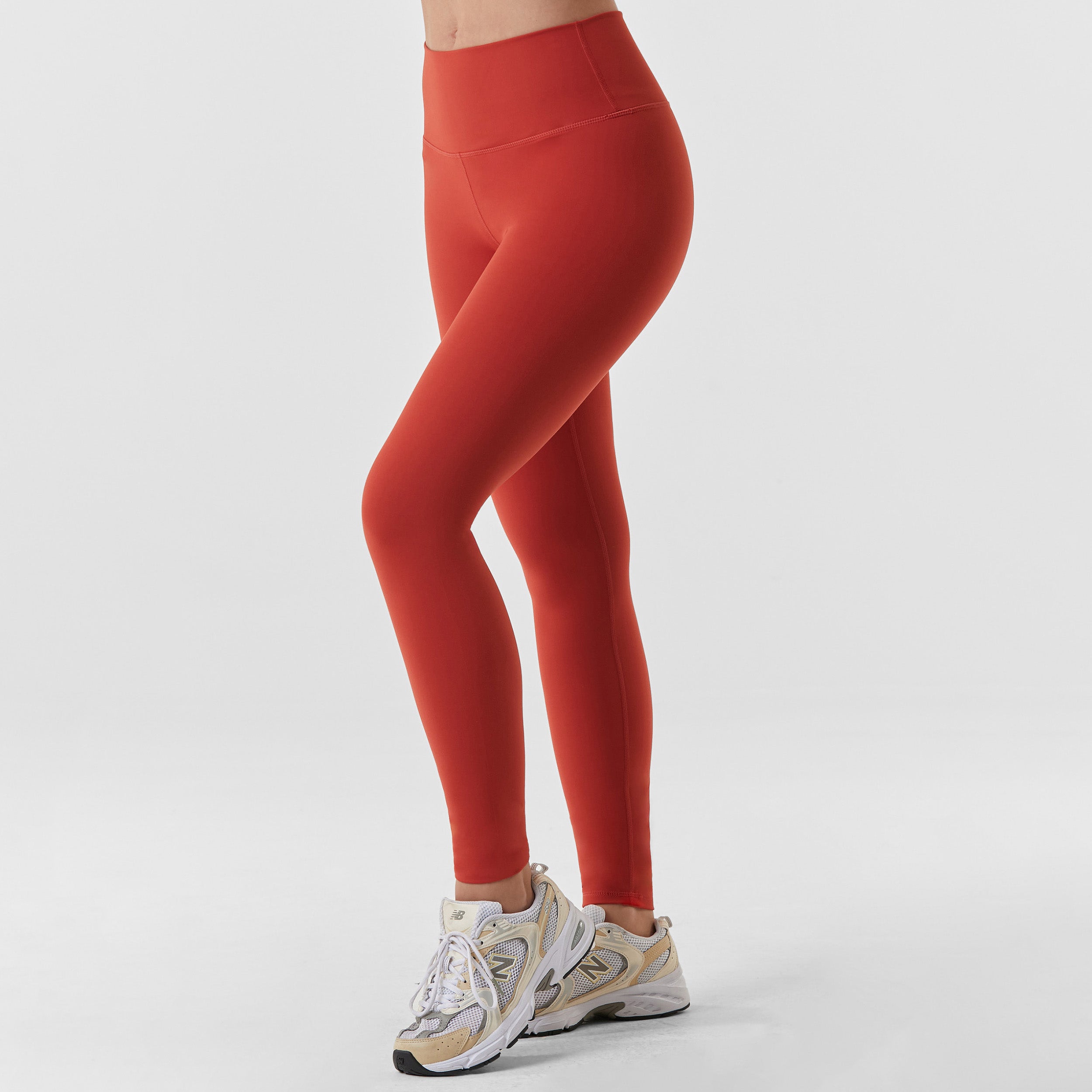 Side view of woman wearing sculpting and flattering brick red legging