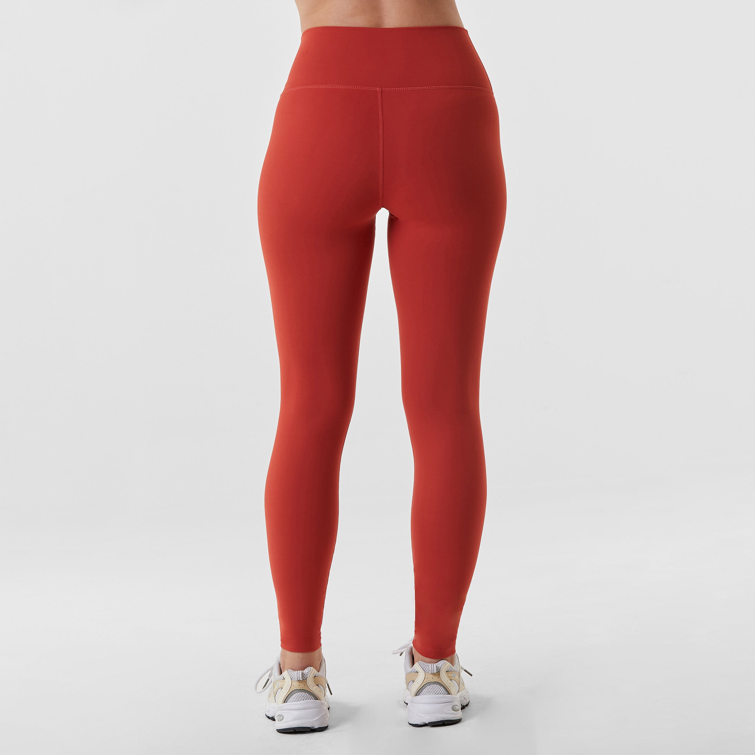 Rear view of woman wearing sculpting and flattering brick red legging