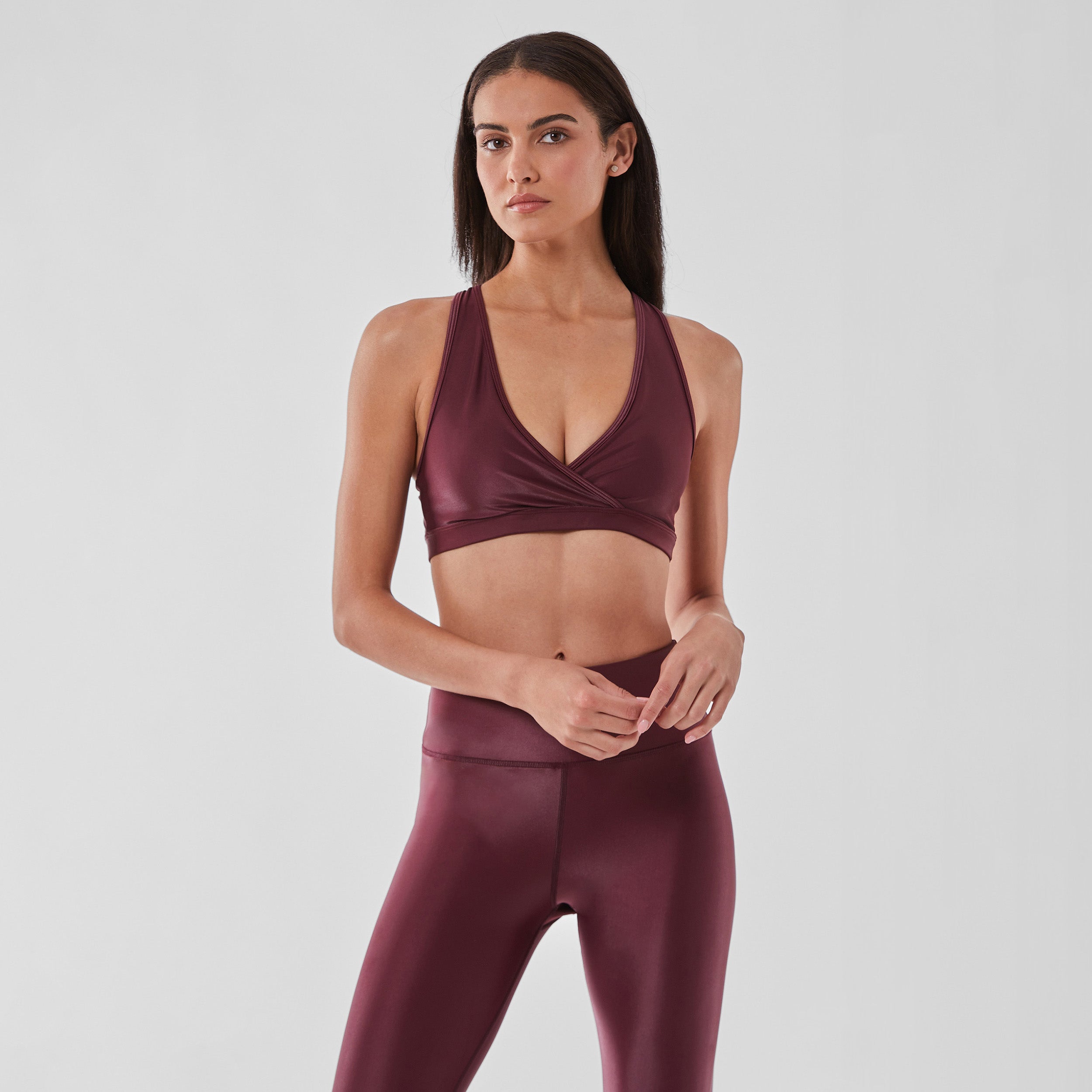 Woman wearing sleek and supportive dark red colored v-neck bra features lightweight and lustrous shine.