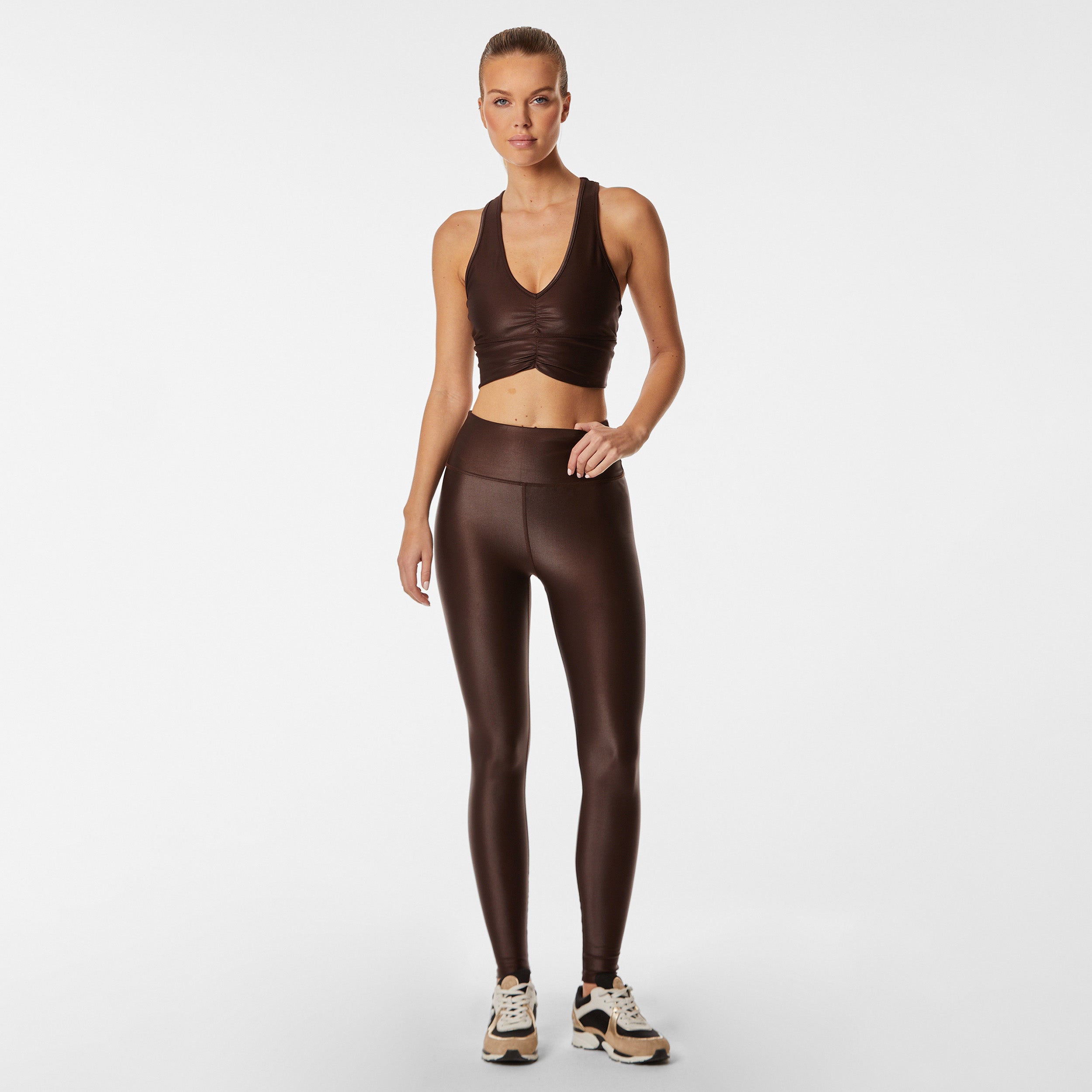 Full body view of woman wearing lightweight, lustrous shine, quick drying dark brown liquid leggings