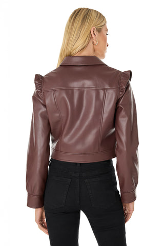 A woman with blonde hair is seen from the back, wearing the Chantal Ruffle Sleeve Leather Jacket in espresso—a chic cropped faux leather style with puffed sleeves—paired with black high-waisted jeans.
