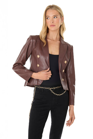 A woman wears the Gabrielle Leather Double Breasted Blazer - Espresso over a black top and pants, styled with a gold chain belt, as she poses against a white background.