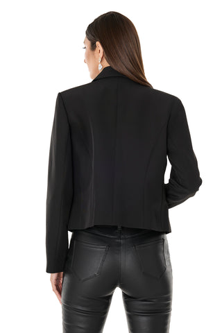 A woman with straight brown hair is shown from the back, wearing the Gabrielle Double Breasted Blazer - Black and black leather pants. She also wears earrings, her left hand at her side, standing against a white background.