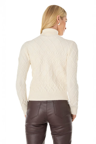 A woman with blonde hair is seen from the back against a white background, wearing the Cara Crystal Sweater in Pearl and dark brown leather pants.