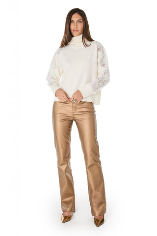 A woman faces forward wearing the Camille Lace Turtleneck Sweater in Pearl, featuring ultra-soft knit lace and delicate sleeve details, styled with shiny gold straight-leg pants and gold pointed-toe heels against a plain white background.