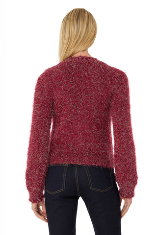 A person with long blonde hair, seen from behind, wears the Joana Knit Cardigan - Merlot and dark blue jeans against a plain white background.