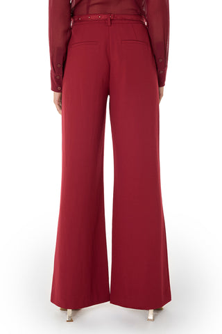 A person is shown from the back wearing the Martina Belted Trouser in Merlot with a matching long-sleeve shirt and white heeled shoes, standing against a white background.