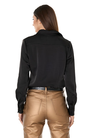 A woman with long brown hair wears the Paulina Silk Blouse in black and shiny gold pants, shown from the back against a white background.