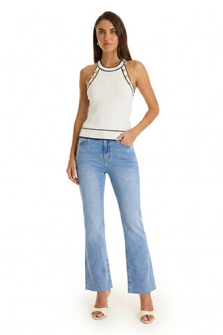 A woman poses in the Martha Button Halter Tank - White, a sleeveless knit top with black trim, styled with light blue flared jeans and beige open-toe heels against a plain white background.