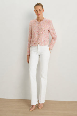 A woman stands against a plain background wearing the May Tweed Crystal Jacket in Pink Multi, paired with white high-waisted pants and nude heels. Her hair is pulled back, and her hands rest at her sides.