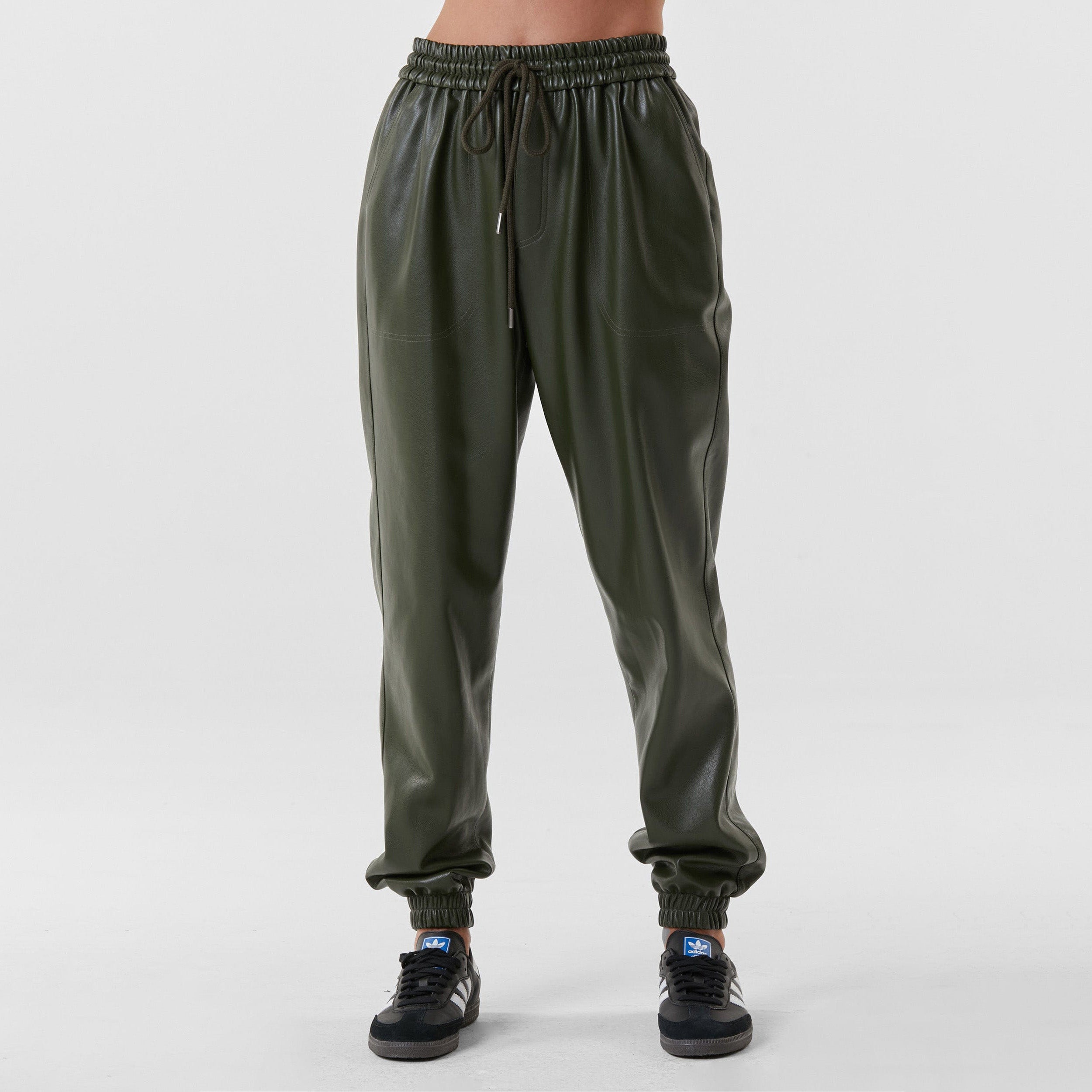 Front view of woman wearing hunter green high rise faux leather jogger with drawstring waistband and cinched ankles with suede lining.