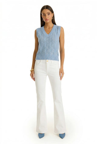 A woman stands facing forward in the Mikaela Crystal Knit Tank in sky blue, paired with white high-waisted flared pants, blue pointed-toe shoes, and gold bracelets against a plain white background.