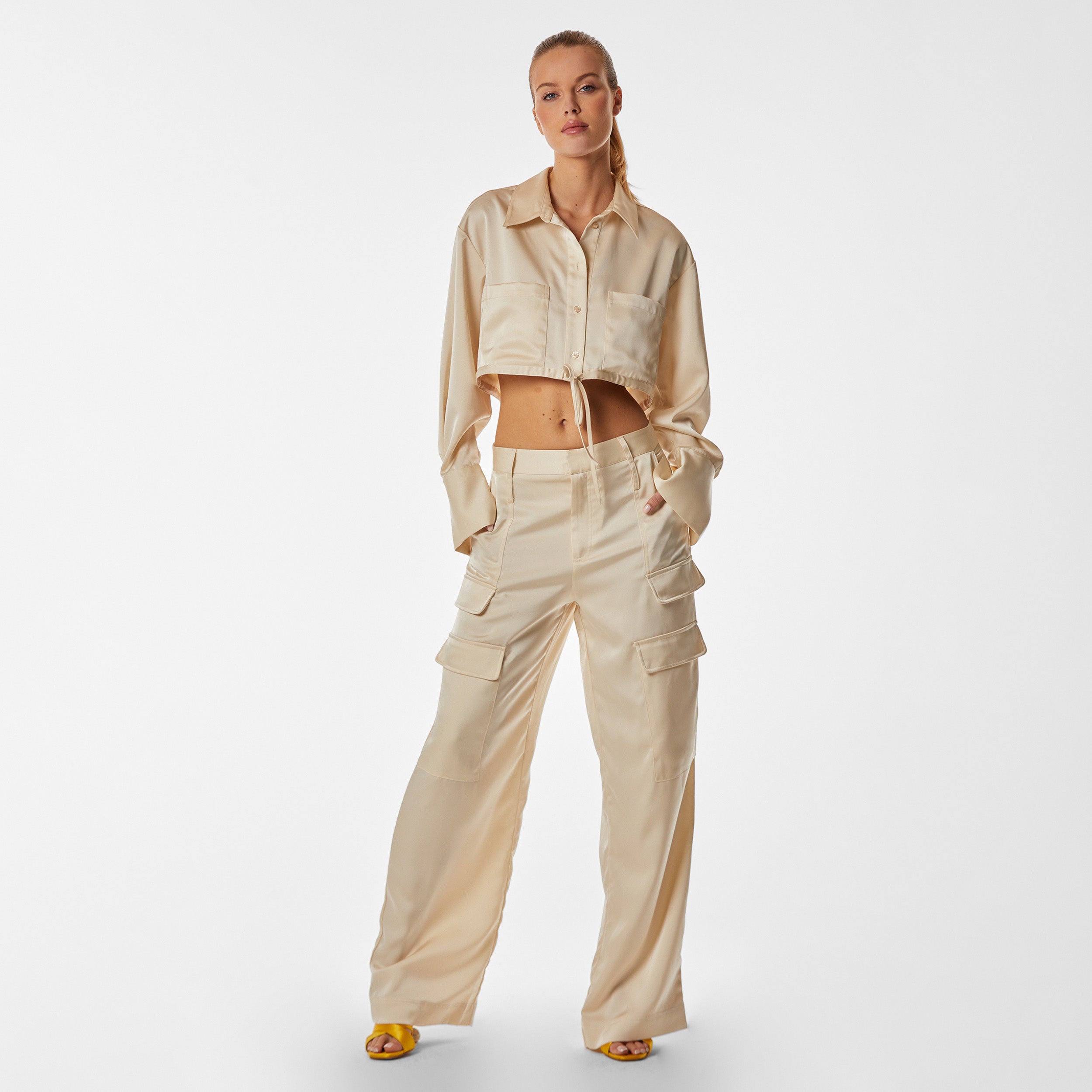 Full body view of woman wearing pearl Milan Satin Button Up features luxurious and structured satin-like fabric, featuring cargo detailing, shell buttons and a tie-waist
