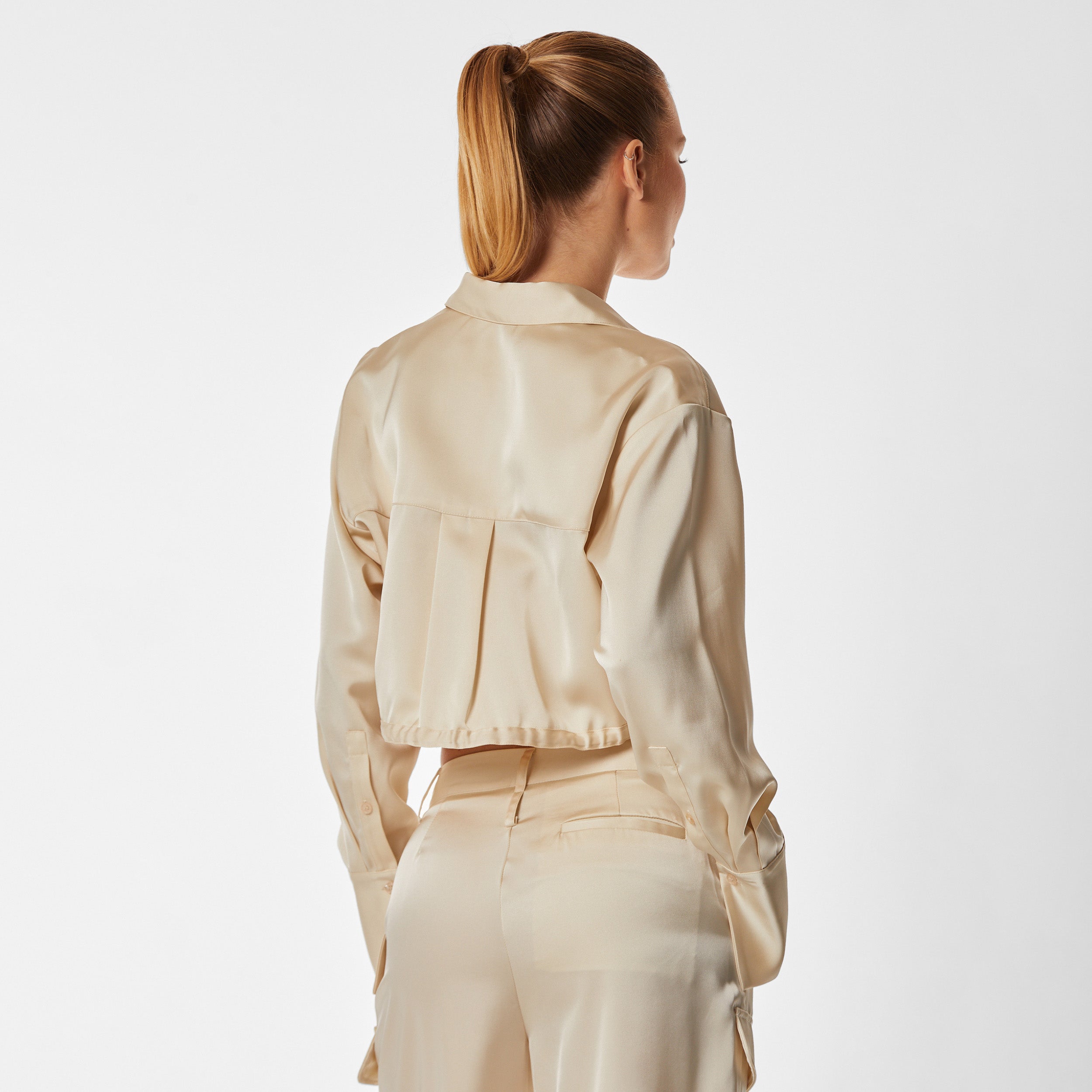 Rear view of woman wearing pearl Milan Satin Button Up features luxurious and structured satin-like fabric, featuring cargo detailing, shell buttons and a tie-waist