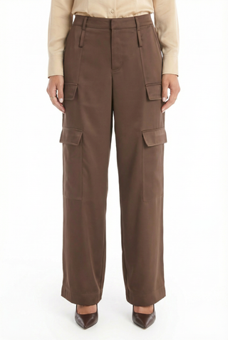 A person is wearing Milan Satin Cargo Pant in Espresso, featuring wide legs and flap pockets, paired with a beige long-sleeve shirt and brown pointed-toe shoes.