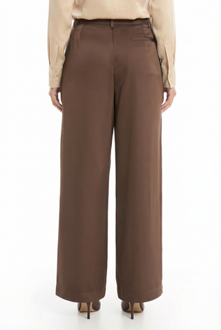 A person shown from the back wears Milan Satin Cargo Pant in Espresso—a wide-leg satin-like style with a single back pocket—paired with a beige shirt and brown heeled shoes.