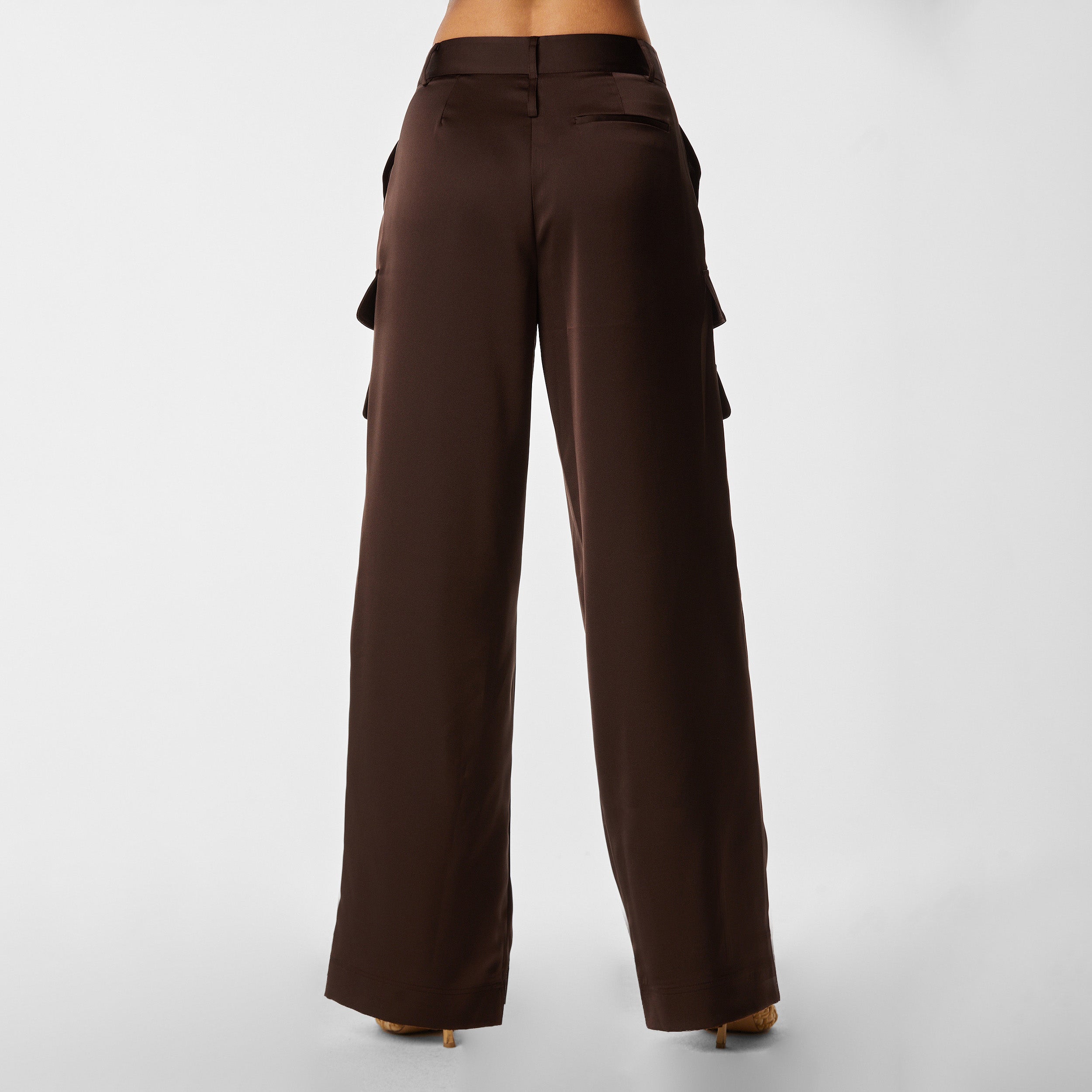 Rear view of woman wearing Brown Satin Milan Pant features Mid-rise with side pockets and cargo detail. Luxurious and structured satin-like fabric. 