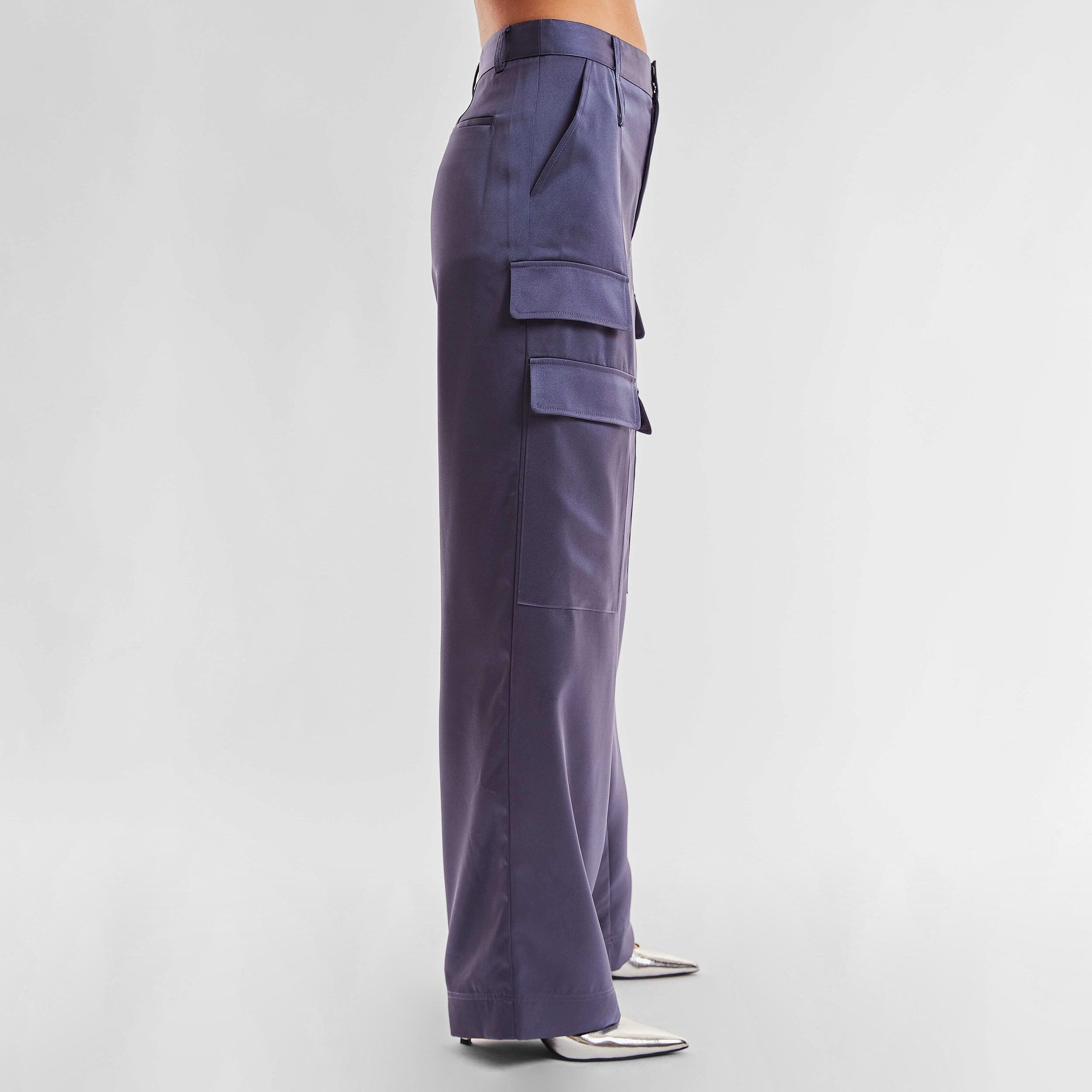 Side view of woman wearing Navy Satin Milan Pant features Mid-rise with side pockets and cargo detail. Luxurious and structured satin-like fabric. 