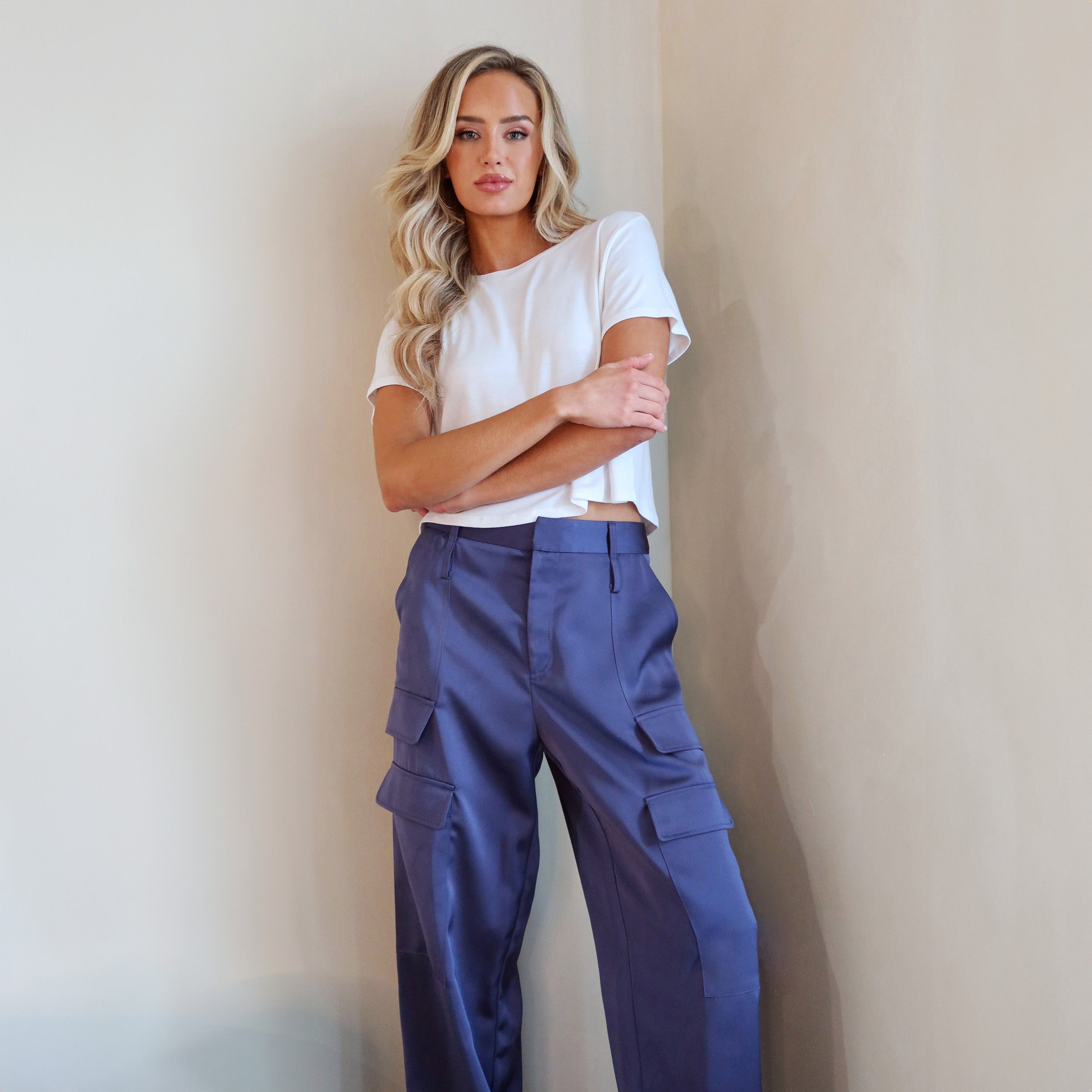 Front view of woman wearing Navy Satin Milan Pant features Mid-rise with side pockets and cargo detail. Luxurious and structured satin-like fabric. 