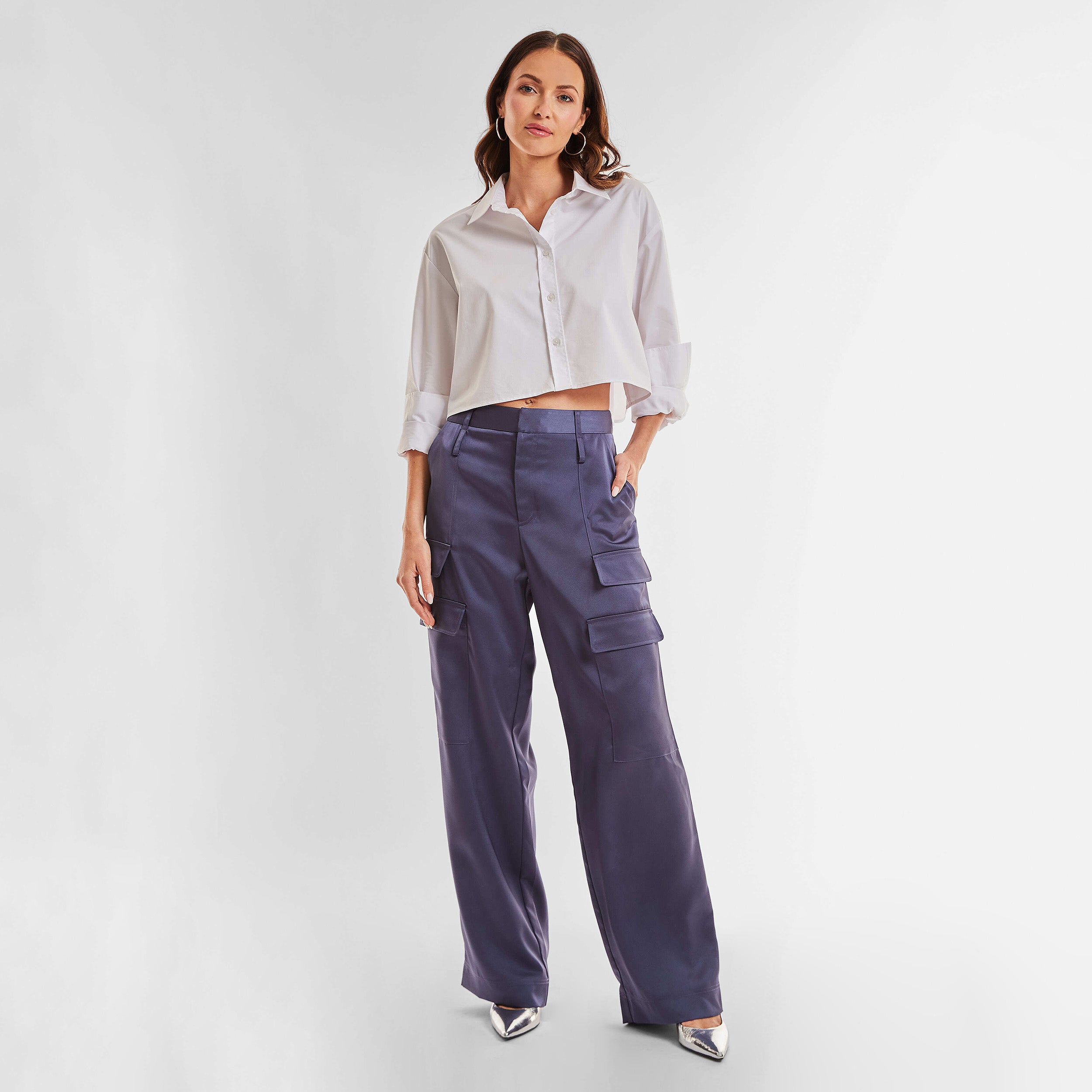 Full view of woman wearing Navy Satin Milan Pant features Mid-rise with side pockets and cargo detail. Luxurious and structured satin-like fabric. 