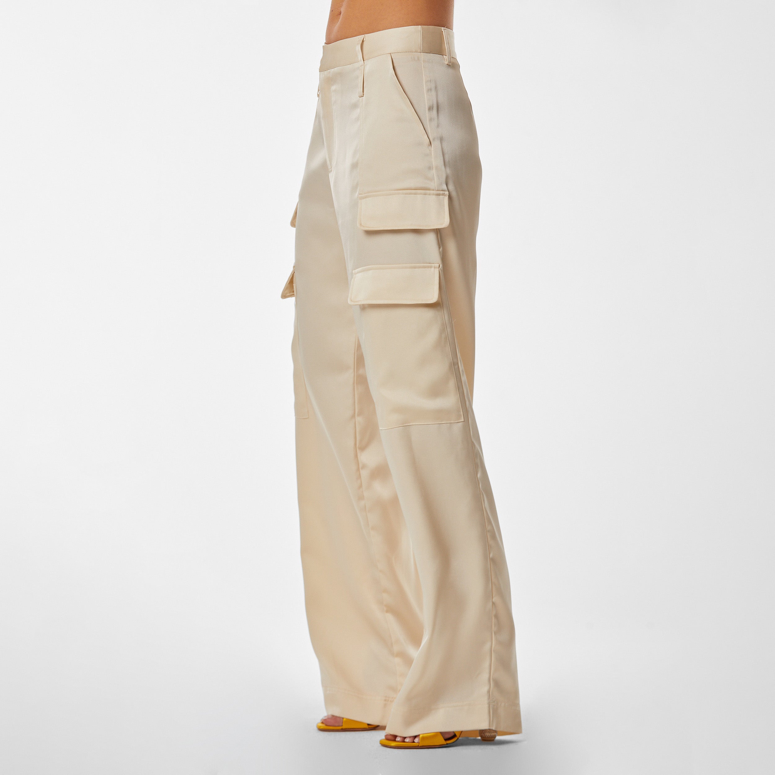 Side view of woman wearing Pearl Satin Milan Pant features Mid-rise with side pockets and cargo detail. Luxurious and structured satin-like fabric. 