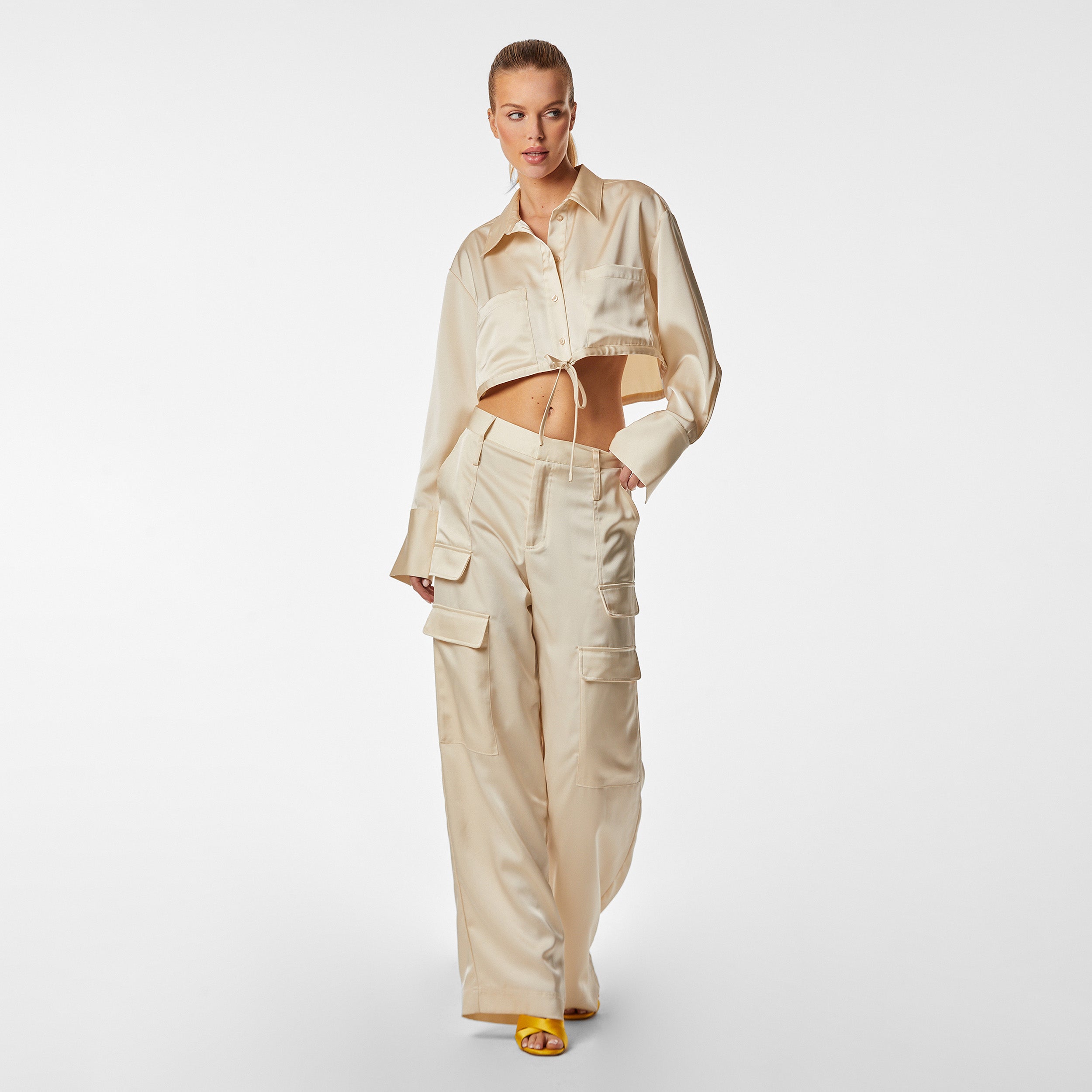 Full view of woman wearing Pearl Satin Milan Pant features Mid-rise with side pockets and cargo detail. Luxurious and structured satin-like fabric. 