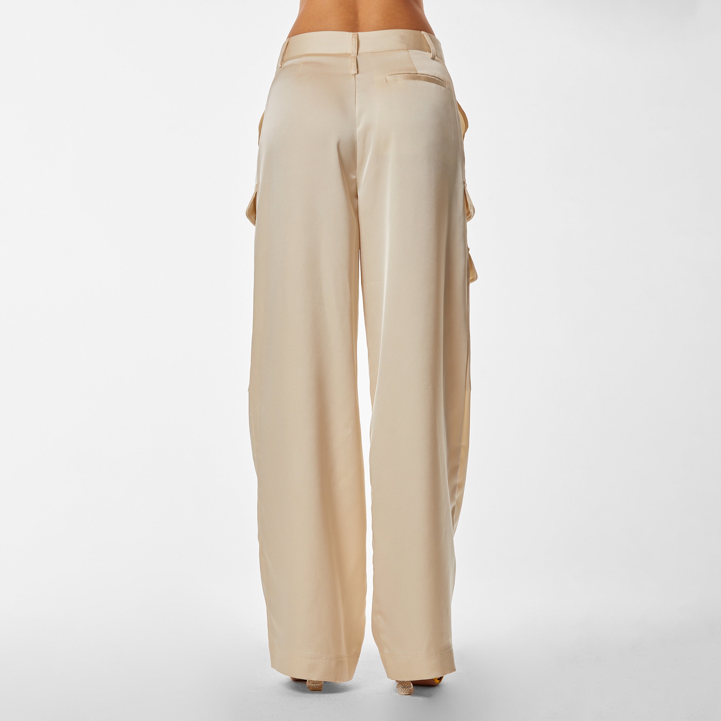 Rear view of woman wearing Pearl Satin Milan Pant features Mid-rise with side pockets and cargo detail. Luxurious and structured satin-like fabric. 