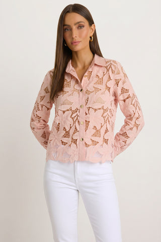 A woman with straight brown hair wears the Mina Lace Blouse - Blush over a matching camisole and high-waisted white pants, standing against a plain light background with a neutral expression.