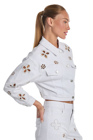 A woman wearing the Kaia Pearl Jean Jacket in white, featuring cropped length and embellished details, stands in profile with her hair in a sleek ponytail against a white background.