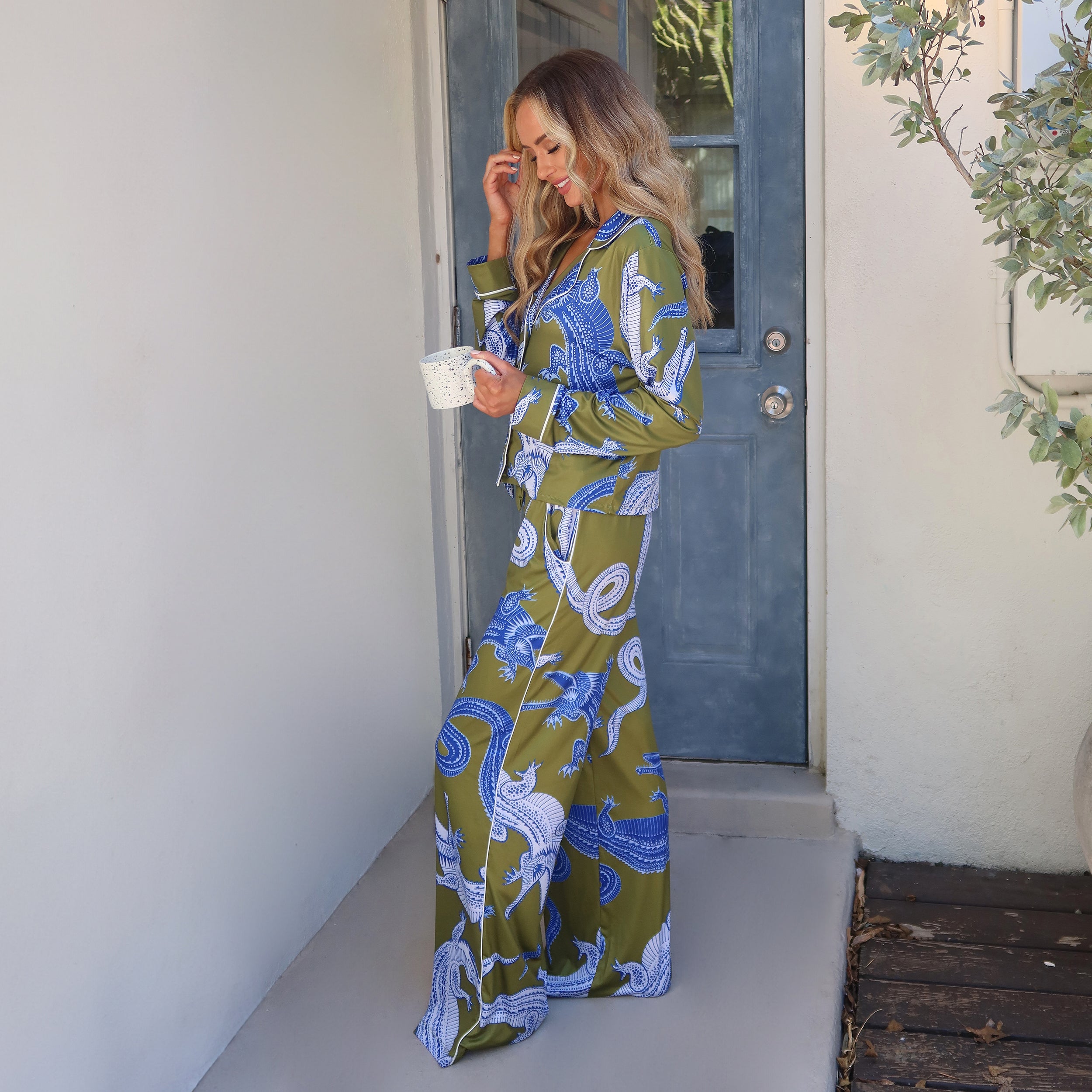 Full view of woman wearing breathable, relaxed and buttery smooth pajama pant featuring high-waist cut, side pockets, front tie and stunning Nile gator print.