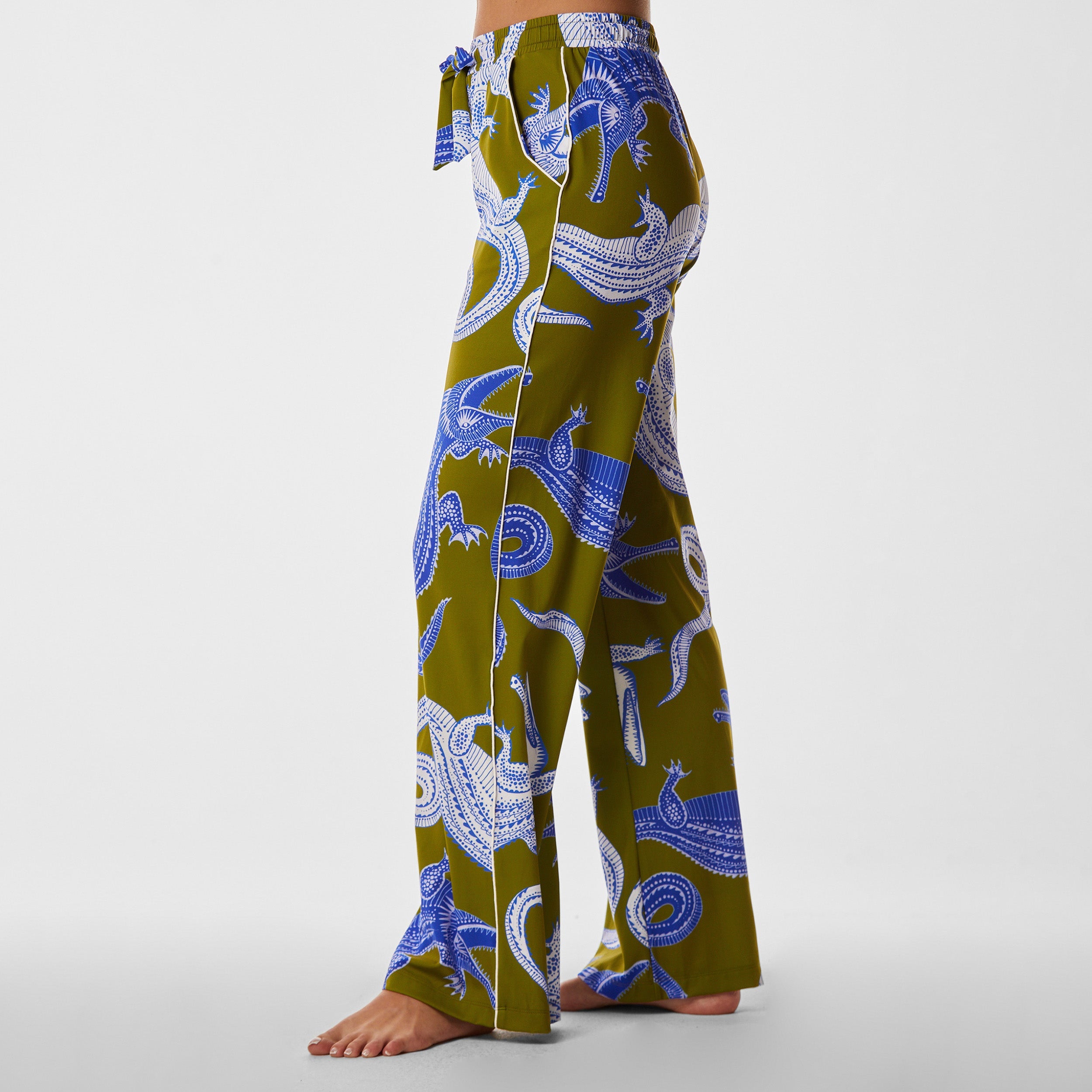 Side view of woman wearing breathable, relaxed and buttery smooth pajama pant featuring high-waist cut, side pockets, front tie and stunning Nile gator print.