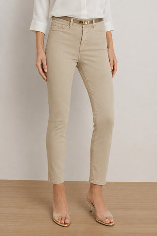Wearing the Nina Cropped Skinny Jean in Oatmeal—a contemporary cropped skinny style made from four-way stretch denim—a person pairs them with a white button-up shirt and clear heeled sandals, standing on a light wooden floor against a plain background.