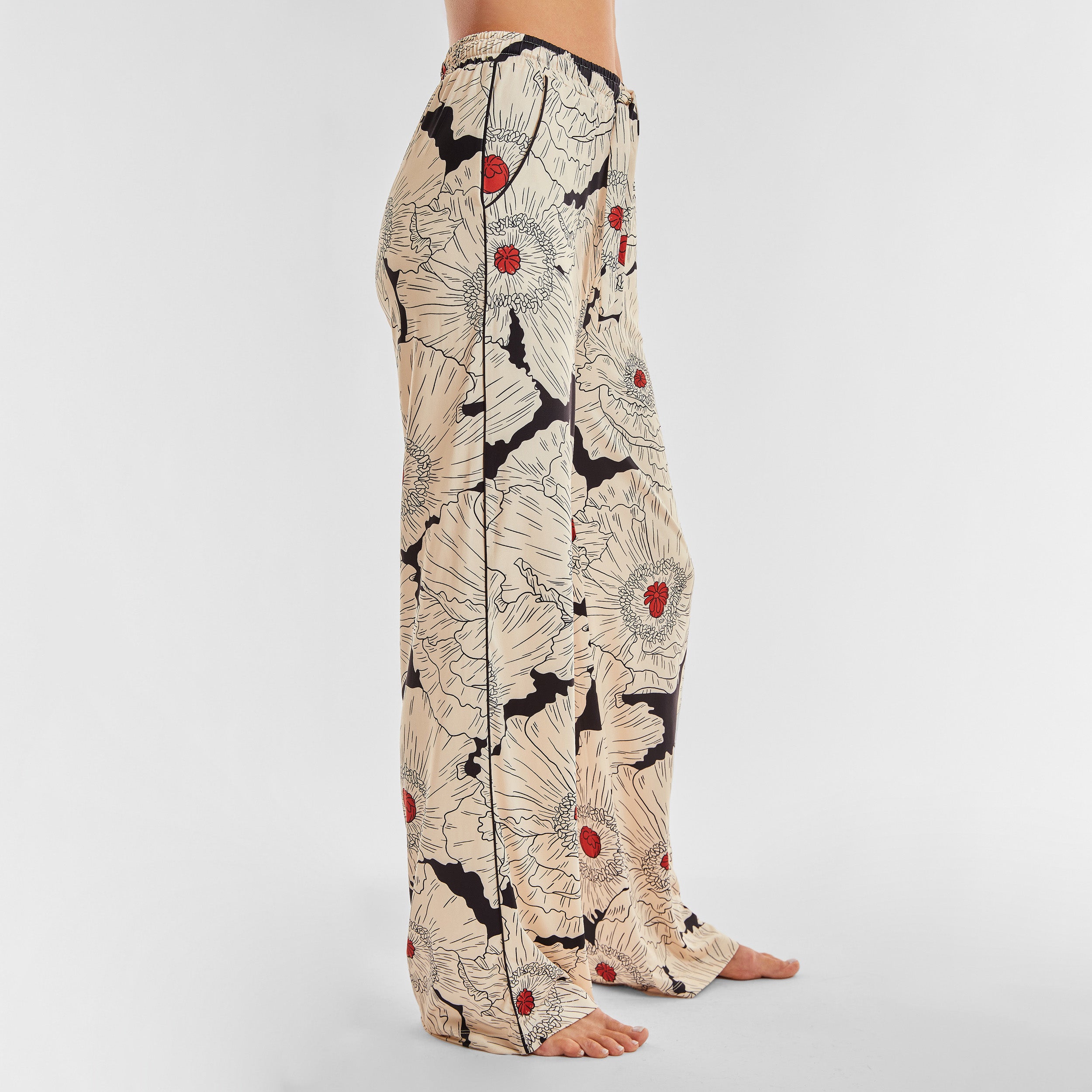 Side view of woman wearing breathable, relaxed and buttery smooth pajama pant featuring high-waist cut, side pockets, front tie and stunning Poppy floral print.