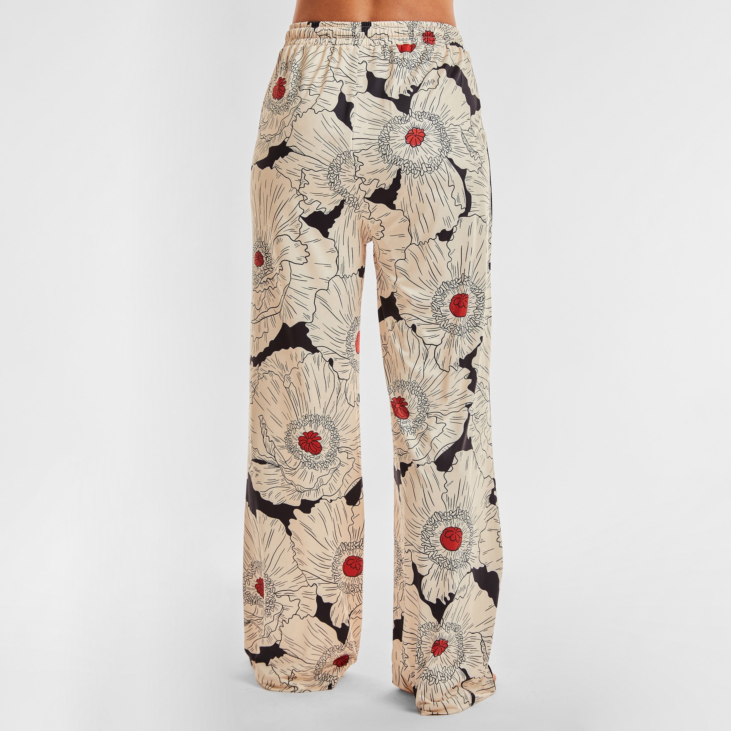Rear view of woman wearing breathable, relaxed and buttery smooth pajama pant featuring high-waist cut, side pockets, front tie and stunning Poppy floral print.