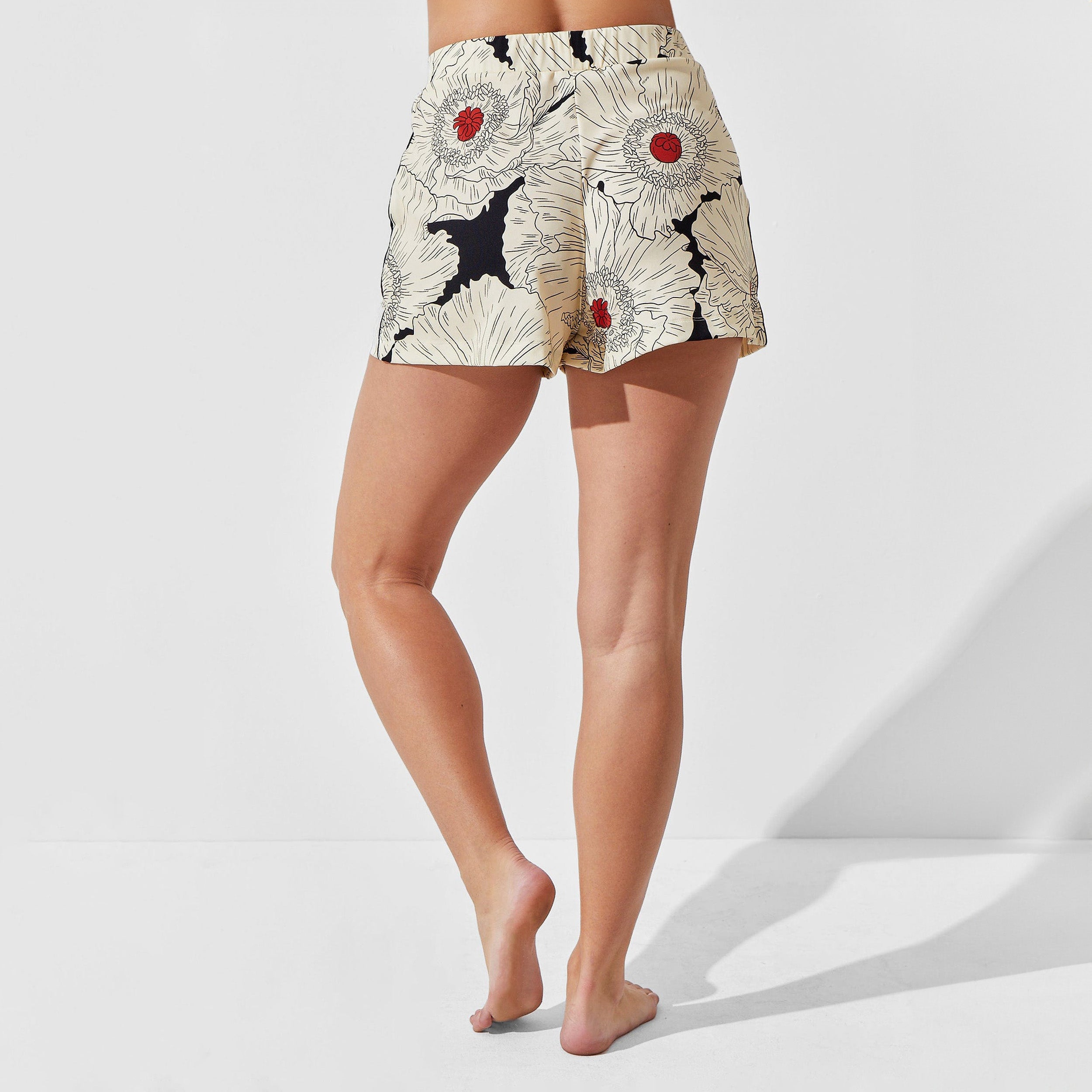 Rear view of woman wearing breathable, relaxed and butter smooth pajama short featuring a high-waist cut, side pockets and stunning Poppy floral print