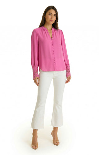 A woman with long brown hair and a neutral expression stands against a white background wearing the Blake Lace Sleeve Blouse in petal pink, paired with white cropped flare pants and clear heeled sandals.