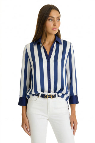 Wearing the Sara Silk Blouse - Navy Stripe, paired with white pants and a black belt, a woman creates a polished silhouette against a white background.