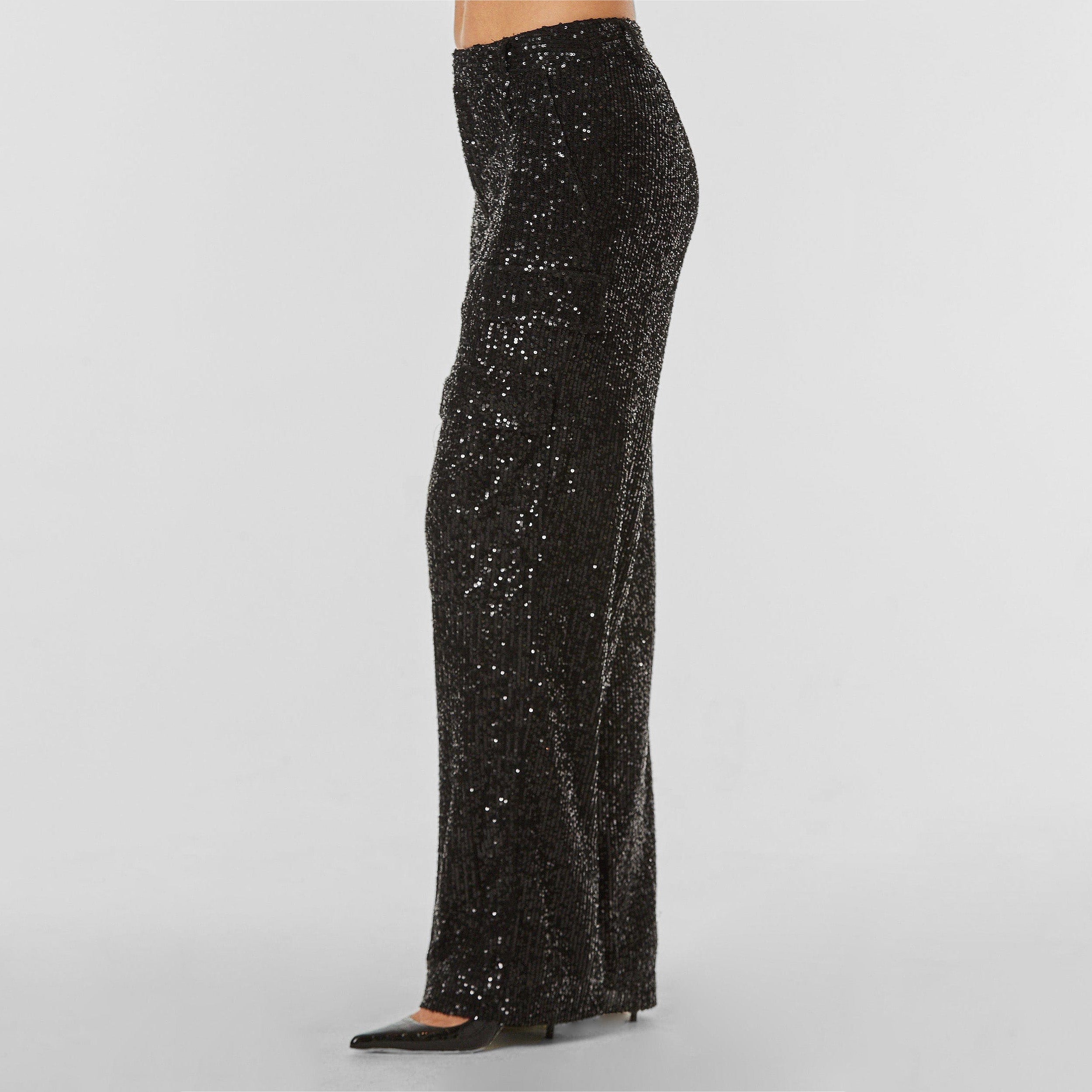 Side view of woman wearing Black Sequin Cargo Pant featuring Mid-rise with side pockets and cargo detail. 