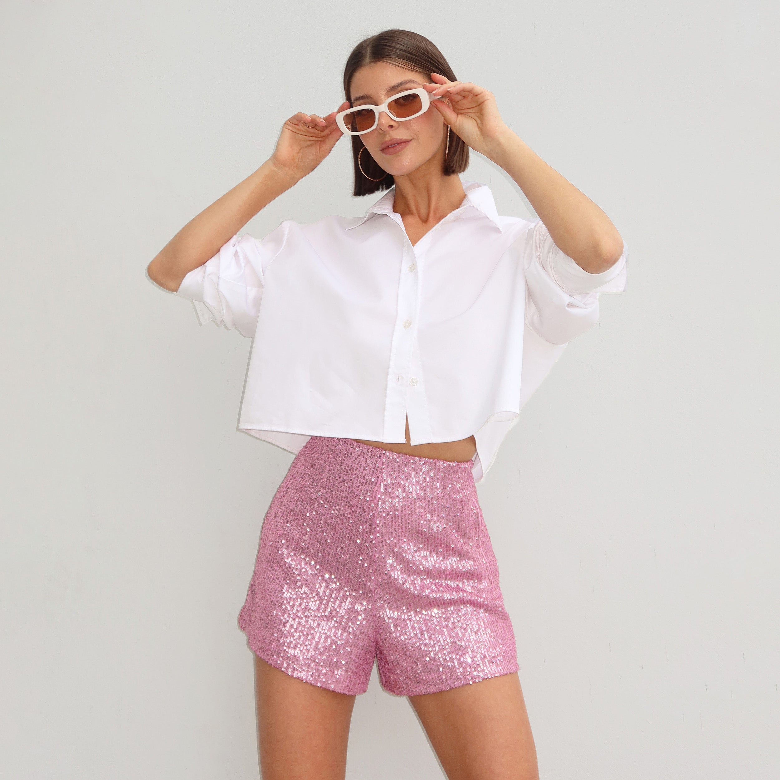 Front view of woman wearing pink shorts with lustrous sequin embroidery