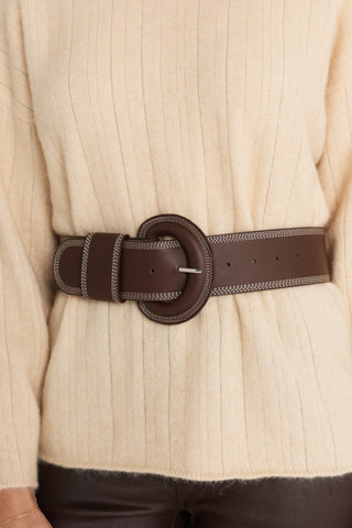 Biarritz Belt in Espresso worn at the waist over the Ingrid Sweater in Latte, close view of the covered round buckle and contrast topstitching