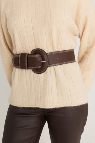 Biarritz Belt in Espresso belted over a latte rib-knit sweater with espresso coated flare jeans, front waist view