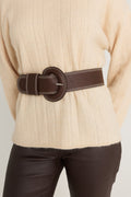 Biarritz Belt in Espresso belted over a latte rib-knit sweater with espresso coated flare jeans, front waist view