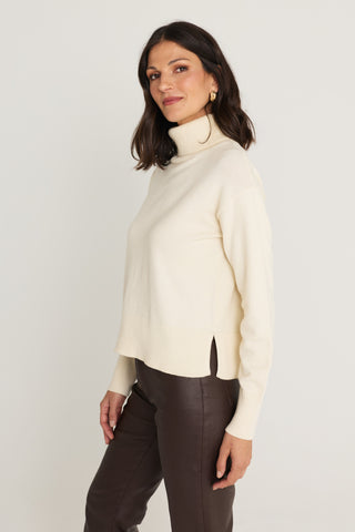 Gia Sweater in Pearl side view showing the ribbed hem and side slit on the ivory turtleneck